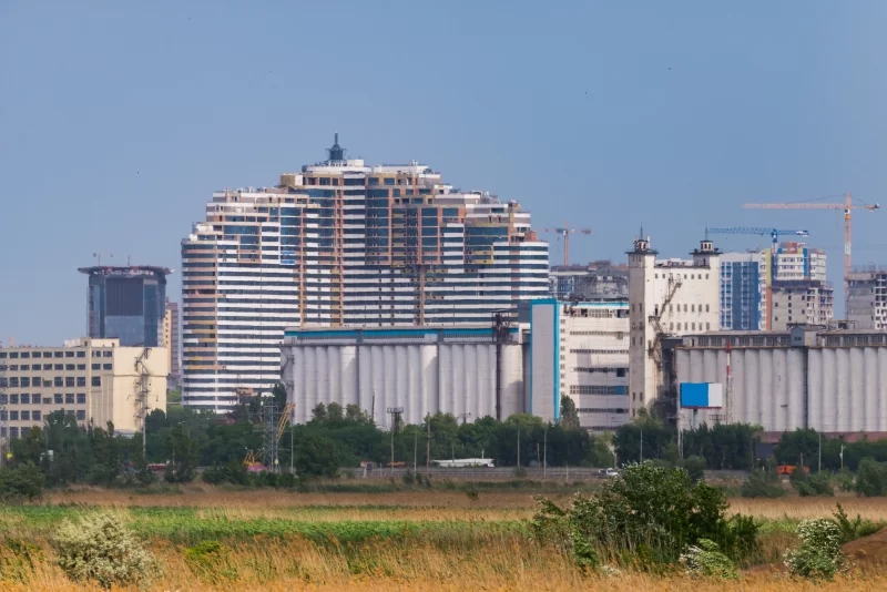 Modern Cityscape with Construction Cranes and Industrial Silos