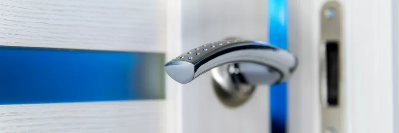 Современная дверная ручка на фоне стеклянной панели с синей вставкой