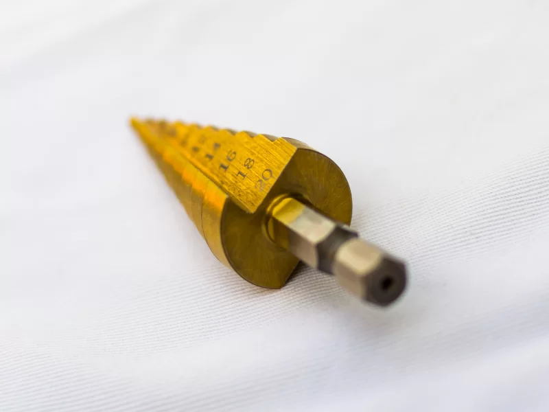 Золотая ступенчатая сверло на белом фоне