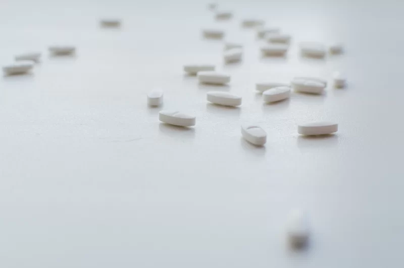 Scattered white pills on a light surface