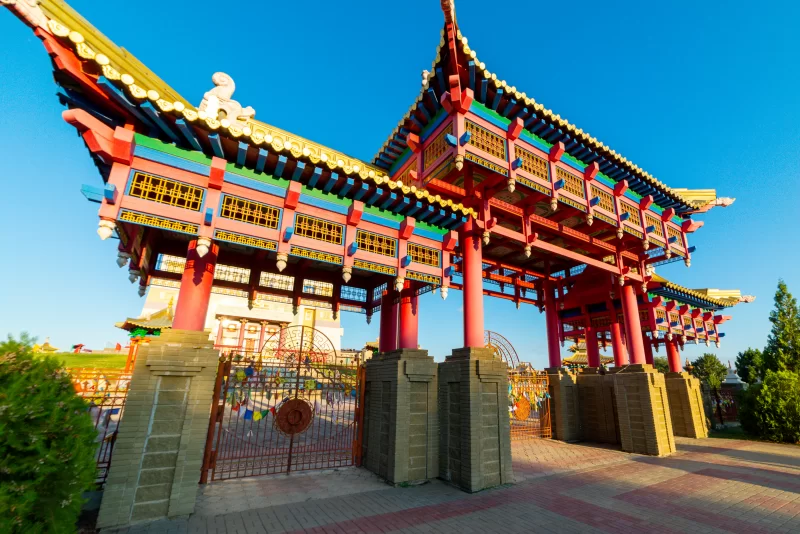 Ворота буддийского храма с орнаментированной крышей и молитвенными флагами