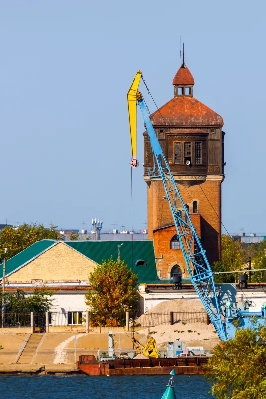 Промышленный кран рядом с исторической водонапорной башней