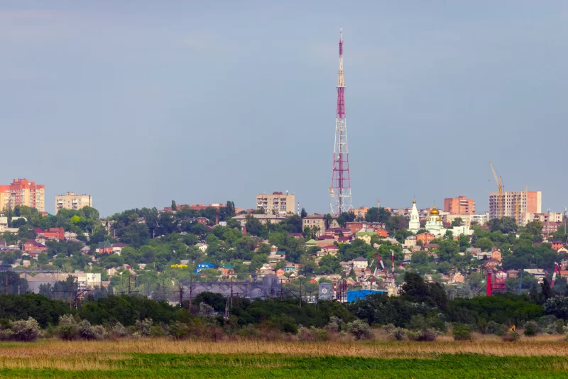 Cityscape with Radio Tower and Green Field