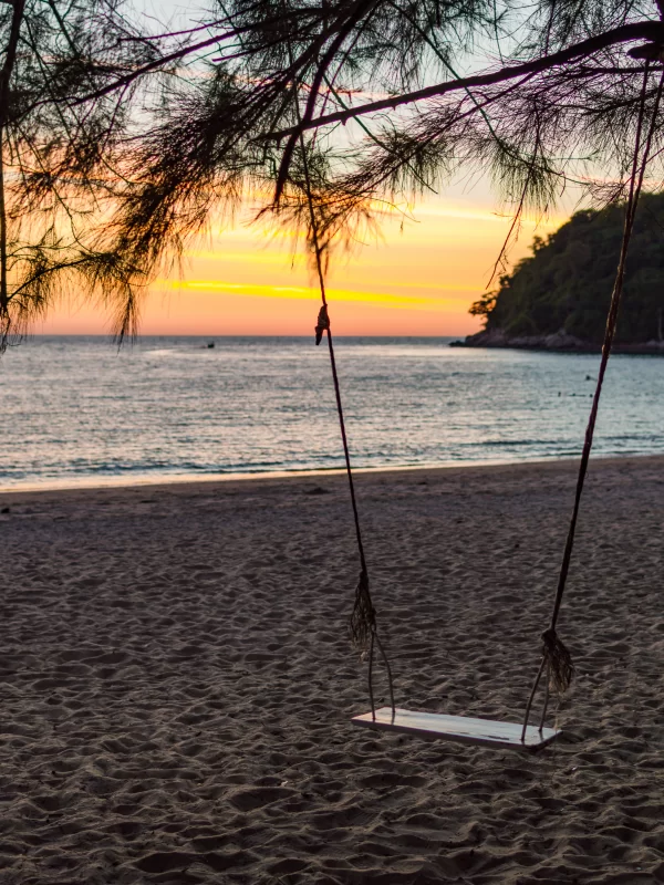 Качели на тропическом пляже во время заката