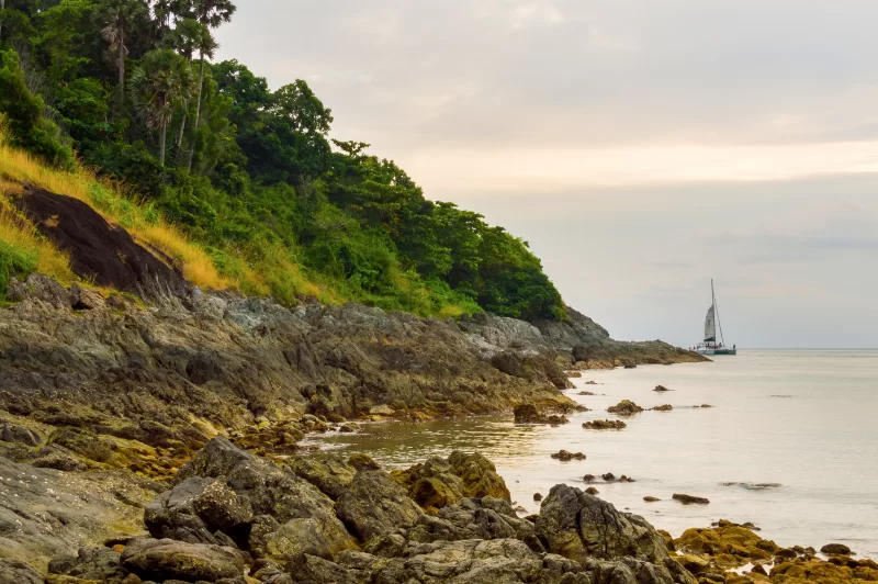 Яхта на спокойном море у скалистого берега