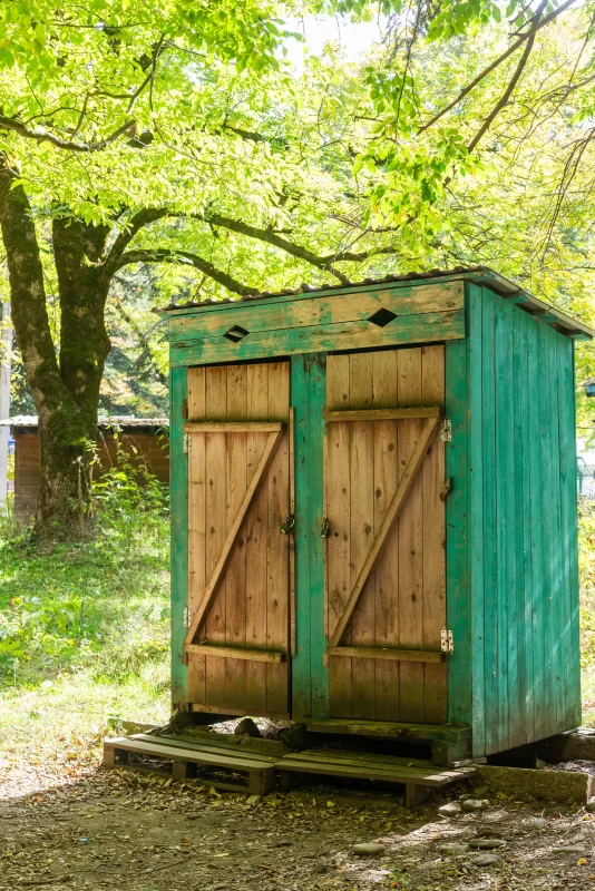 Старинная деревянная будка в зеленом саду под солнечными лучами