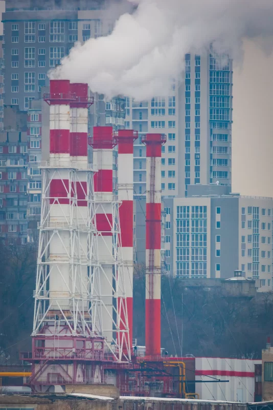 Дымящие трубы теплоэлектростанции на фоне современных жилых домов