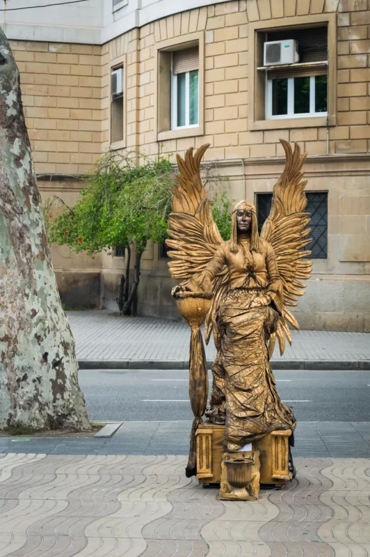 Золотая живая статуя ангела на оживленной улице Барселоны