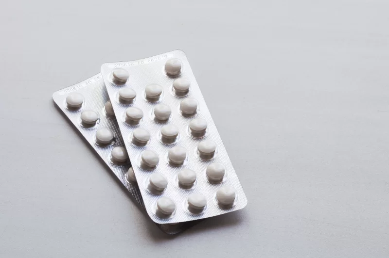 Two blister packs of pills on a light background
