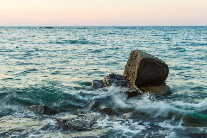 Брызги волны на камнях на закате
