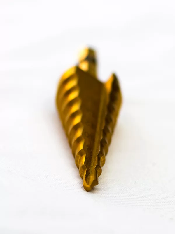 Золотая ступенчатая сверло на белом фоне