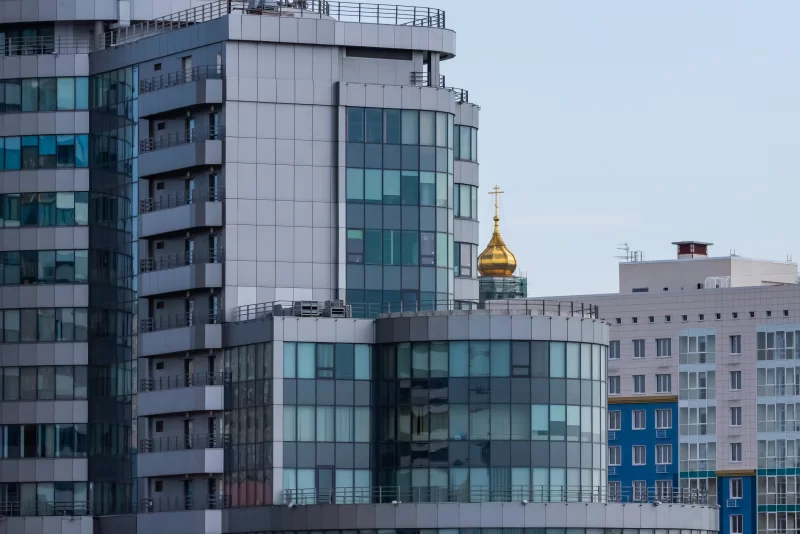 Modern high-rise building with golden dome of Orthodox church