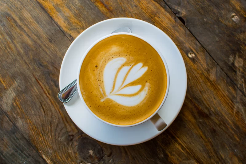 Идеальный латте-арт: чашка кофе на текстурном деревянном столе