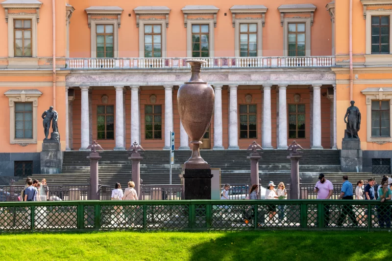 Античный фасад здания с вазой и людьми