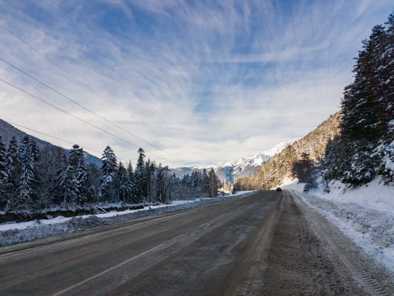 Зимняя дорога в горах с снежными деревьями